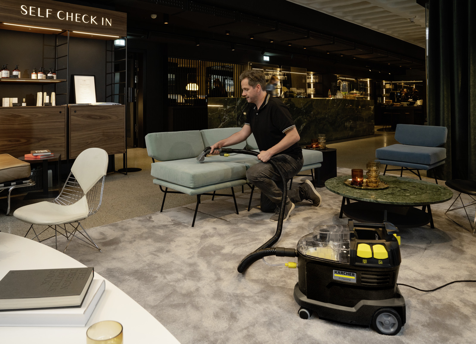 Profesjonalne urządzenie ekstrakcyjne Puzzi 8/1 C firmy Karcher Profesjonalne urządzenie ekstrakcyjne Puzzi 8/1 C firmy Karcher. Kobieta znosi Puzzi 8/1 C po schodach.