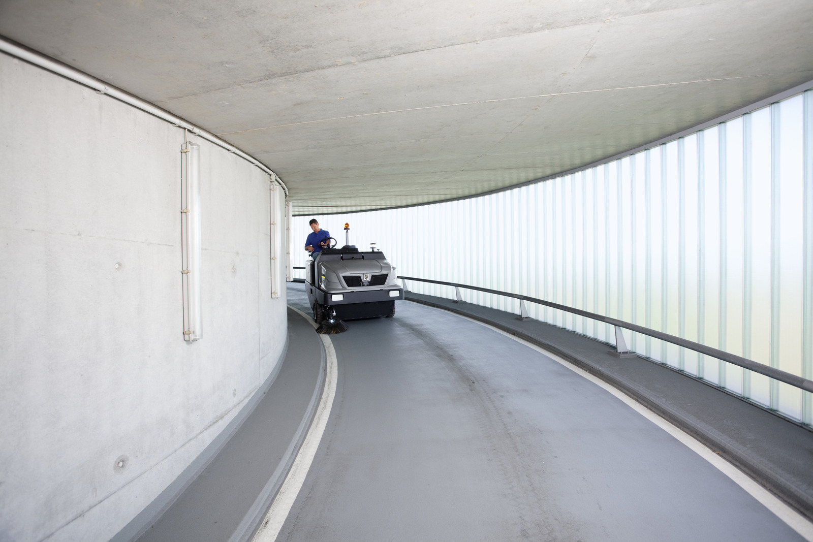 Profesjonalna, zamiatarka przemysłowa KM 150/500 R Bp firmy Karcher z napędem Diesla. Mężczyzna jedzie urządzeniem zamiatając drogę przy pomocy przemysłowej zamiatarki KM 150/500 R D firmy Karcher.