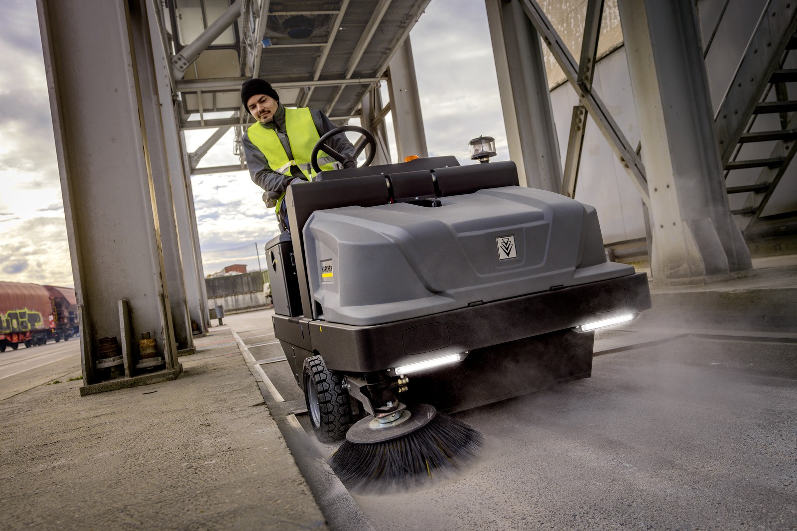 Profesjonalna, zamiatarka przemysłowa KM 130/300 R D firmy Karcher z napędem Diesla. Profesjonalna, zamiatarka przemysłowa KM 130/300 R D firmy Karcher z napędem Diesla. Mężczyzna jedzie urządzeniem zamiatając plac przy sortowni odpadów komunalnych za pomocą przemysłowej zamiatarki KM 130/300 R D firmy Karcher.